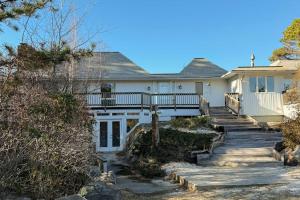 a white house with stairs leading up to it at La Casa De La Playa in Gloucester