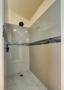 a bathroom with a shower with white walls and tile floors at Tortuga Amarilla 1 in Maya Beach