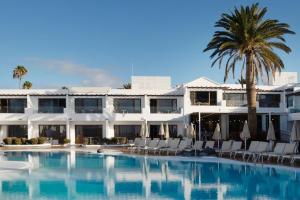 a resort with a swimming pool with chairs and a palm tree at R2 Bahia Kontiki in Puerto del Carmen