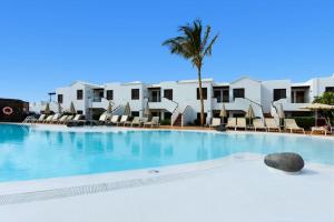 a large swimming pool with chairs and a palm tree at R2 Bahia Kontiki in Puerto del Carmen