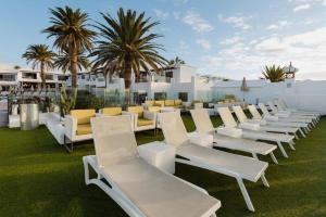 a row of white lounge chairs sitting on the grass at R2 Bahia Kontiki in Puerto del Carmen