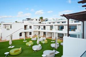 a building with a lawn with chairs and tables at R2 Bahia Kontiki in Puerto del Carmen +33 photos