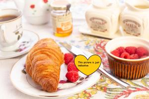 a plate with a croissant and raspberries on a table at Room country-lake in Dormelletto