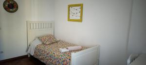 a small bed in a bedroom with a clock on the wall at Vieiras House Quarto Solteiro in Barreiro