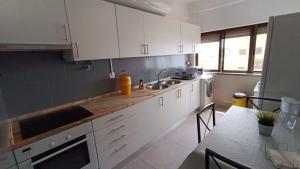 a kitchen with white cabinets and a sink and a counter at Vieiras House Quarto Solteiro in Barreiro