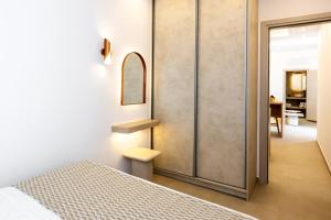 a bedroom with a bed and a mirror on a wall at Caldera Jewel Santorini in Firostefani +43 photos