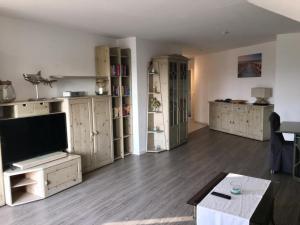 a living room with a flat screen tv and wooden floors at NTBM36104-FeWo-Swalkennest in Neue Tiefe Fehmarn