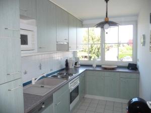 a kitchen with green cabinets and a sink and a window at NTBM36104-FeWo-Swalkennest in Neue Tiefe Fehmarn