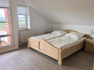 a bedroom with a wooden bed in a room with a window at NTBM36104-FeWo-Swalkennest in Neue Tiefe Fehmarn