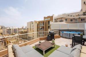 a balcony with a couch and a table on a building at Bright 3BR Penthouse with Pool & BBQ in Msida by QuickTrips in Misraħ Il-Barrieri