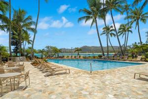 a pool at the resort with palm trees and chairs at Beachfront Lae Nani 3BD Condo AC & Heated Pool in Kapaa