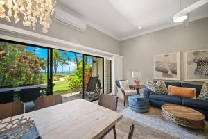 a living room with a blue couch and a table at Beachfront Lae Nani 3BD Condo AC & Heated Pool in Kapaa +51 photos