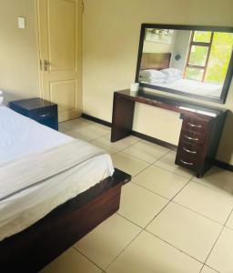 a bedroom with a bed and a dresser and a mirror at Folang Resort in Centurion