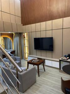 a living room with a tv and a couch and a table at Brava Hotel in Ibadan