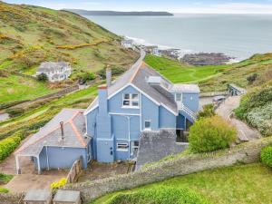a blue house on a hill next to the ocean at 1 Bed in Mortehoe oc-barri in Mortehoe +4 photos