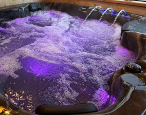 a bath tub filled with purple water and bubbles at Bukowiańska Ostoja Jacuzzi Sauna i Balia w Ofercie, 60m od Wyciągów in Bukowina Tatrzańska