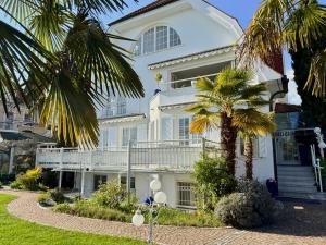 a white house with palm trees in front of it at Boutique Hotel Villa am See in Hagnau
