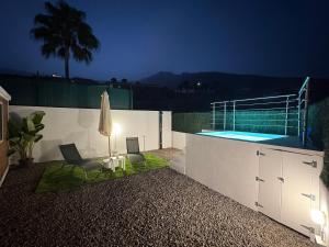 a swimming pool with two chairs and a table and a umbrella at Casa Hoya de Carta in Candelaria +9 photos