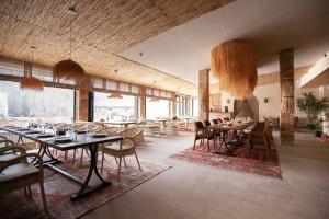 a dining room with tables and chairs and large windows at By Tau in Almaty