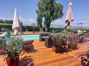a patio with potted plants and umbrellas next to a pool at La Clef Des Anges 2 Chambres in Égliseneuve-près-Billom