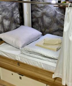 a bed with white sheets and pillows on it at KING City Center Hostel in Baku