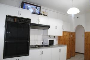 a kitchen with white cabinets and a black appliance at Tatami Guesthouse in Parow