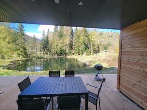 a table and chairs on a deck with a view of a lake at Chalet des Briseux in Saint-Maurice-sur-Moselle