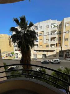 a palm tree in front of a building with cars at Appartement Belle vue 3 Meknès in Meknès