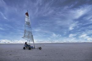 a person riding a small sail boat on the beach at les pins in Quend