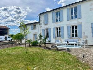 a white house with blue windows and a yard at La Barauderie , chambre individuelle in Mazeray