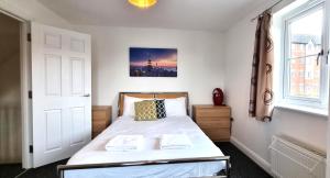 a bedroom with a bed with white sheets and a window at Spacious 4 Bedroom House, Old Town in Swindon