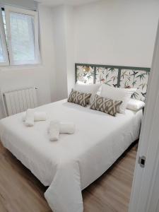 a white bed with white sheets and pillows at El Pinar Beach in Comillas