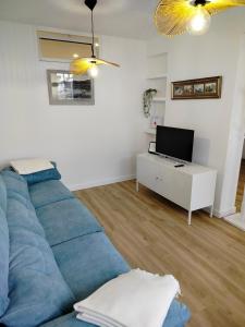 a living room with a blue couch and a tv at El Pinar Beach in Comillas