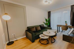 a living room with a green couch and a table at Lumea Noir - Designer Apartment in Timișoara in Timişoara