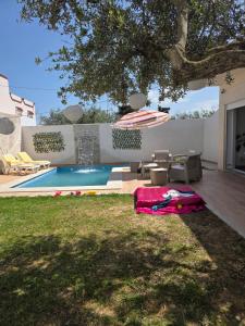 a backyard with a swimming pool and an umbrella at Villa Maya House - Cap Zbib in Banī ‘Aţāʼ