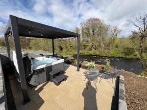 a hot tub on a patio next to a river at The Bleach Green Cottage in Drumahoe