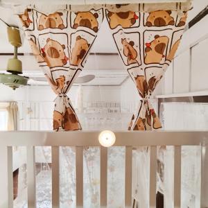 a room with a crib with curtains and a ceiling at NiranHouse Hostel in Sathani Phitsanulok