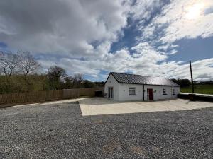 a white garage with a fence and a cloudy sky at The Bleach Green Cottage in Drumahoe +8 photos