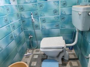 a bathroom with a toilet and blue tiled walls at The Fortune Mango in Jajpur Road