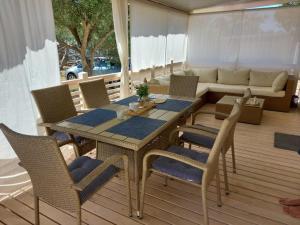 a table and chairs on a deck with a couch at Regina Mobile Home 3 Bedrooms, 100m to Beach, Family Friendly in Sveti Filip i Jakov
