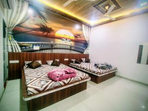 two beds in a room with a painting on the wall at Hotel Manasvi in Khātu +6 photos