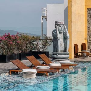 a statue next to a pool with chairs and a statue at Hotel Wins Apec Phú Yên in Tuy Hoa