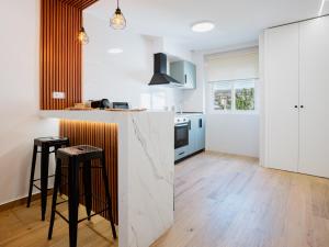 a kitchen with white walls and a counter with stools at El Rinconcito de mi Alma in Caravaca de la Cruz