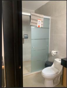 a bathroom with a toilet and a glass shower at Complejo Las Flores in Durango