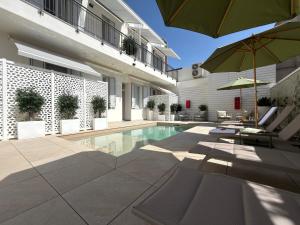 a house with a swimming pool with chairs and an umbrella at Mesbeglia Luxury Rooms in Alghero