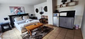 a bedroom with a bed and a table and a kitchen at The Mansion Lodge in Hartbeespoort