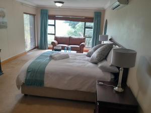 a bedroom with a large bed with a chair and a window at The Mansion Lodge in Hartbeespoort