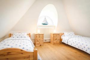 two twin beds in a room with a window at Reethus-am-Hafen Reetdachhaus Hafenblick mit Garten und Blick aufs Wasser in Rankwitz