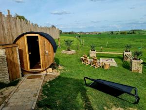 a wooden hobbit house in a field with a fence at Tiny cocon en pleine nature jacuzzi, sauna privé in Tinlot