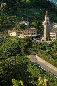 a town on a hill with a road and a clock tower at B&B Gastaldo di Rolle in Cison di Valmarino